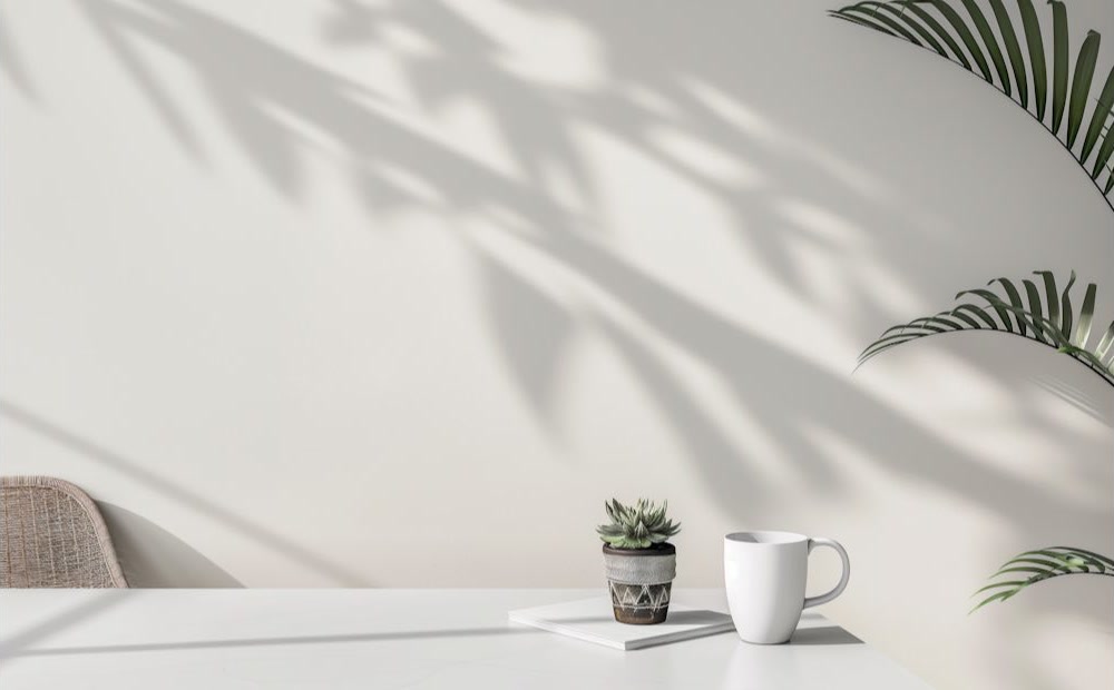 A small plant and a cup on a sunlit apartment desk